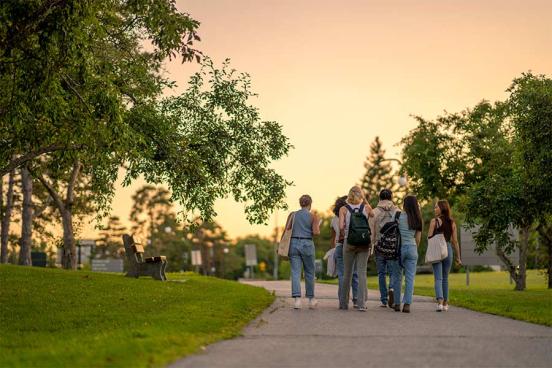 A group of college students is seen walking through campus at sunset