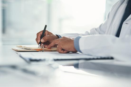 A doctor wearing a lab coat writes notes