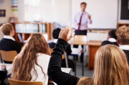 High school classroom with teen girl raising hand