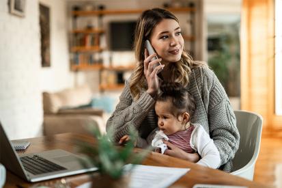 A young mother talks on the phone while her child in her lap