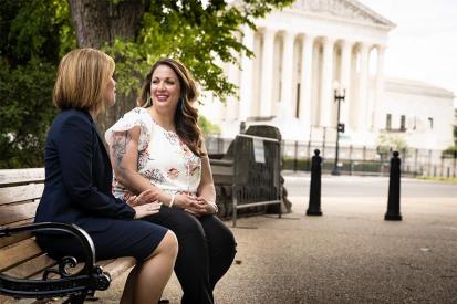 Kristen Waggoner and Lorie Smith sit on a bench outside of the Supreme Court building in Washington, D.C.