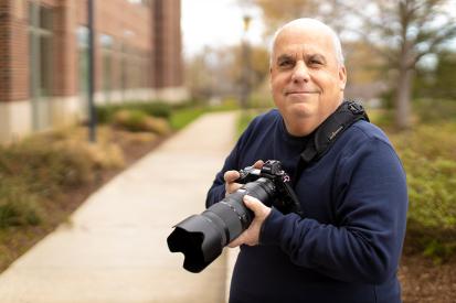 Bob Updegrove holding his camera on a sidewalk