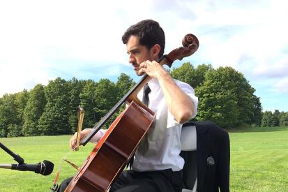 Indiana music and orchestra teacher John Kluge playing the cello outdoors