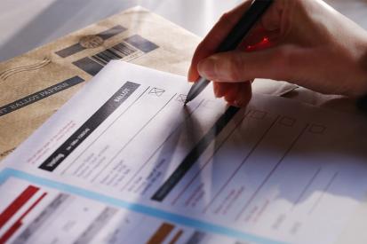 A voter is seen filling out a ballot