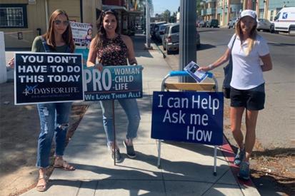 Sidewalk counselors with Right to Life of Central California stand with signs on a sidewalk