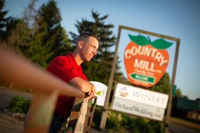 Steve Tennes of Country Mill Farms stands in front of his family farm's sign