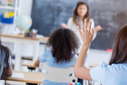 A student is seen raising her hand in class