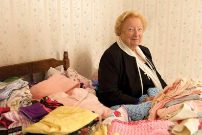 Eleanor McCullen sitting on a bed with baby clothes