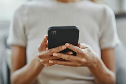 A woman is seen looking a phone she's holding in her hands