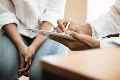 A doctor takes notes as he meets with an adolescent patient