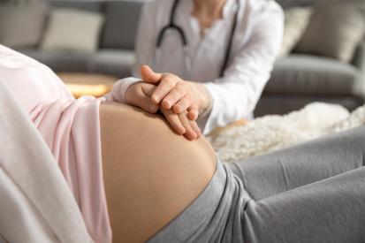 Pregnant woman with a doctor placing their hands on the mother's womb