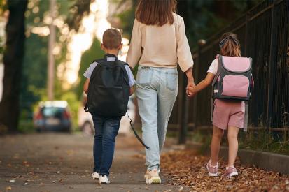 Mother with her two children walking down a path to school