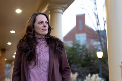 Elizabeth Gillette stands on a porch looking into the distance on a cloudy day