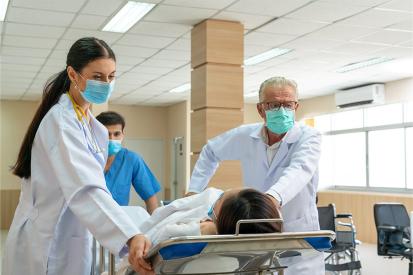 Medical professionals in a hospital wheel a patient down a hallway in a stretcher