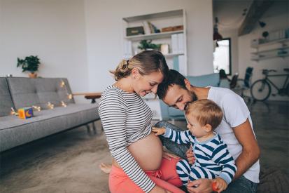 A toddler with his parents touches his mother's pregnant belly