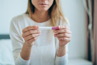 A woman looks down at a pregnancy test