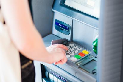 A woman swipes her credit card at an ATM