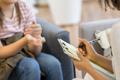 A counselor takes notes while speaking with a minor