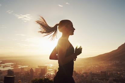 Female athlete running overlooking city into the sun