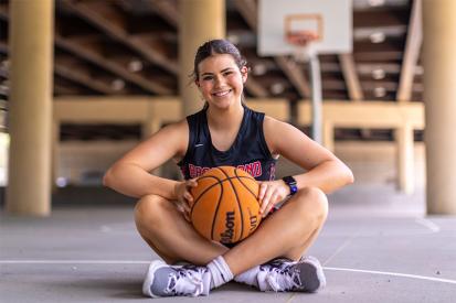 Amelia Ford sits on the court holding a basketball