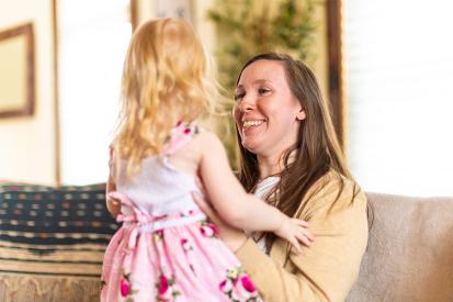 Katy Wuoti smiles and holds her daughter