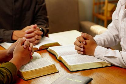 People sit together praying and reading the Bible