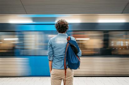 A man stands at a train station as a train goes by