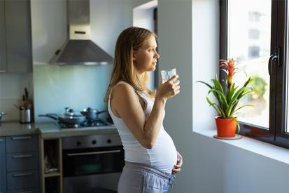 A pregnant woman is pictured in her kitchen looking out the window