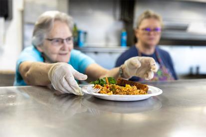 Workers in the kitchen serve a plate of food at Yakima Union Gospel Mission