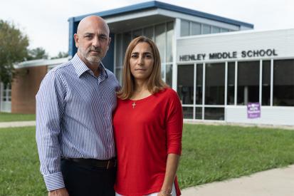 Carlos and Tatiana Ibanez stand in front of Henley Middle School with serious expressions on their faces