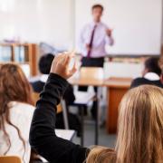 High school classroom with teen girl raising hand