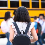 Girl with a backpack getting on the school bus