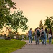 A group of college students is seen walking through campus at sunset