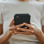 A woman is seen looking a phone she's holding in her hands