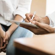 A doctor takes notes as he meets with an adolescent patient