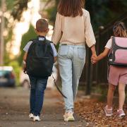 Mother with her two children walking down a path to school