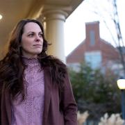 Elizabeth Gillette stands on a porch looking into the distance on a cloudy day