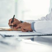 A doctor wearing a lab coat writes notes