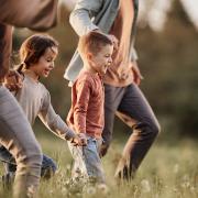 A mom and dad and their two kids run through a sunny field