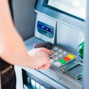 A woman swipes her credit card at an ATM