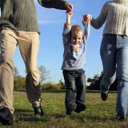 A young boy holding his parents' hands