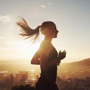 Female athlete running overlooking city into the sun