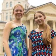 Sisters Aubrey and Avalon Simpson stand in front of the Kansas State Capitol