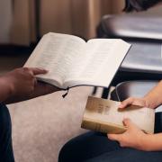 Two people study the Bible together in a classroom