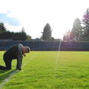 Coach Joe Kennedy kneels on the football field at Bremerton High School in Washington