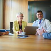 A group of doctors and other health-care professionals sit around a table