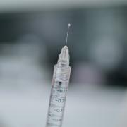 A syringe is seen against a blurry gray background