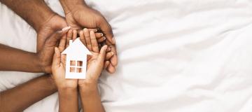 Hands holding a house symbolizing foster care