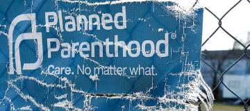 A Planned Parenthood banner on a chain link fence