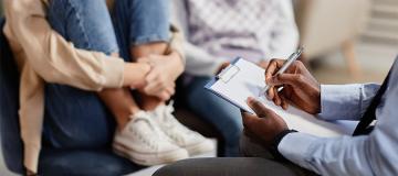 A counselor takes notes as he talks with a child and parent